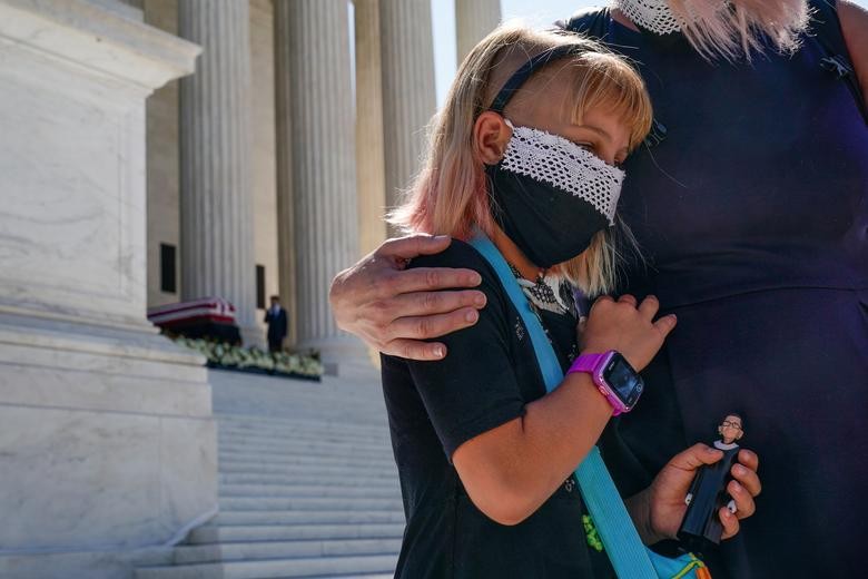 Neva Gotwals-Ferrei, 8, embraces her mother while holding a Justice Ruth Bader Ginsburg doll at the Supreme Court. REUTERS/Erin Scott    